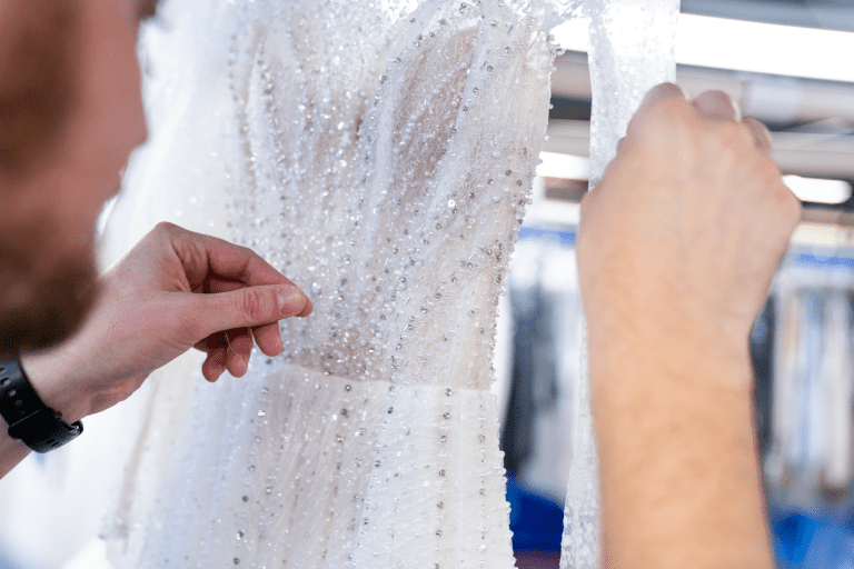 man repairing wedding dress during dry cleaning