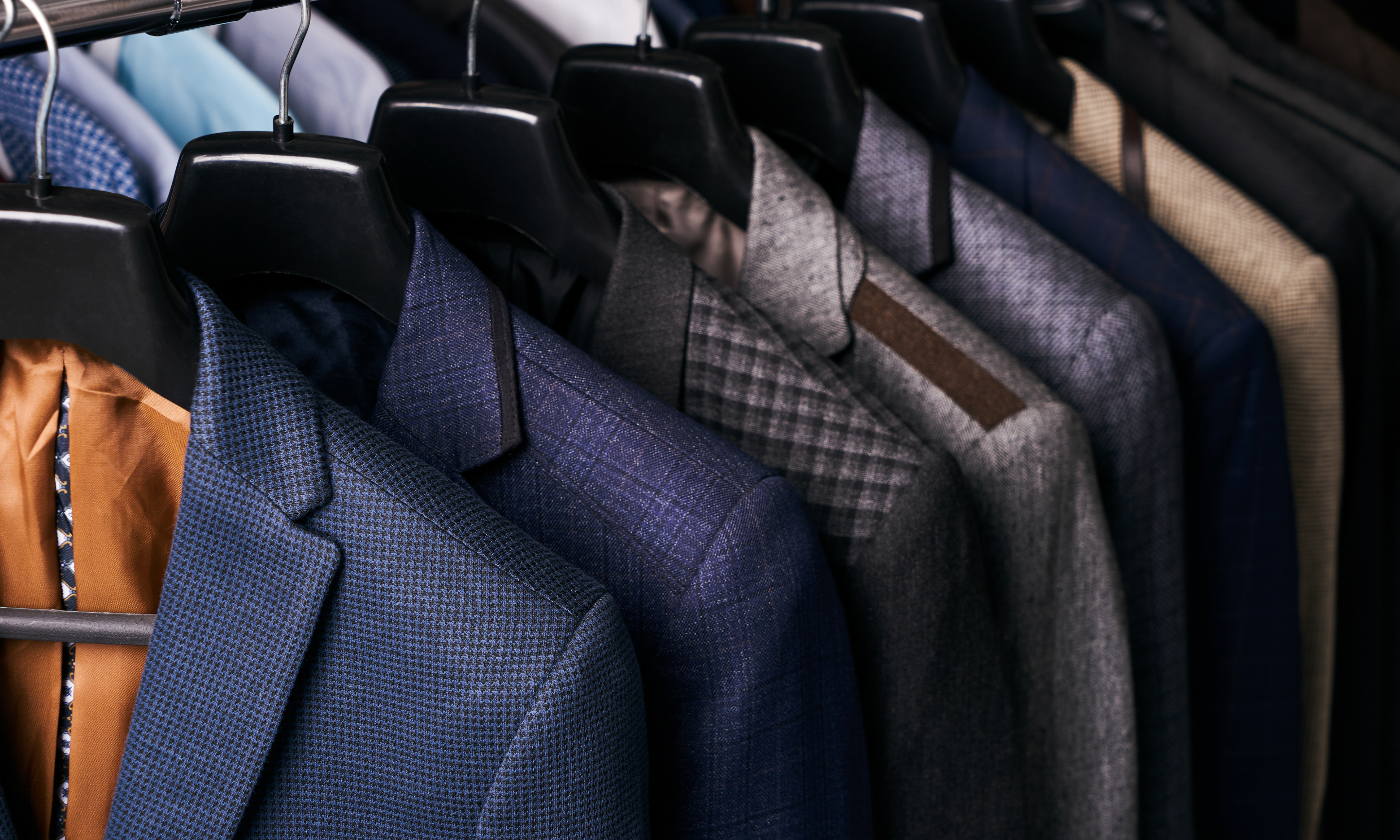 dry cleaned suits hanging next to each other on a rack at Keans