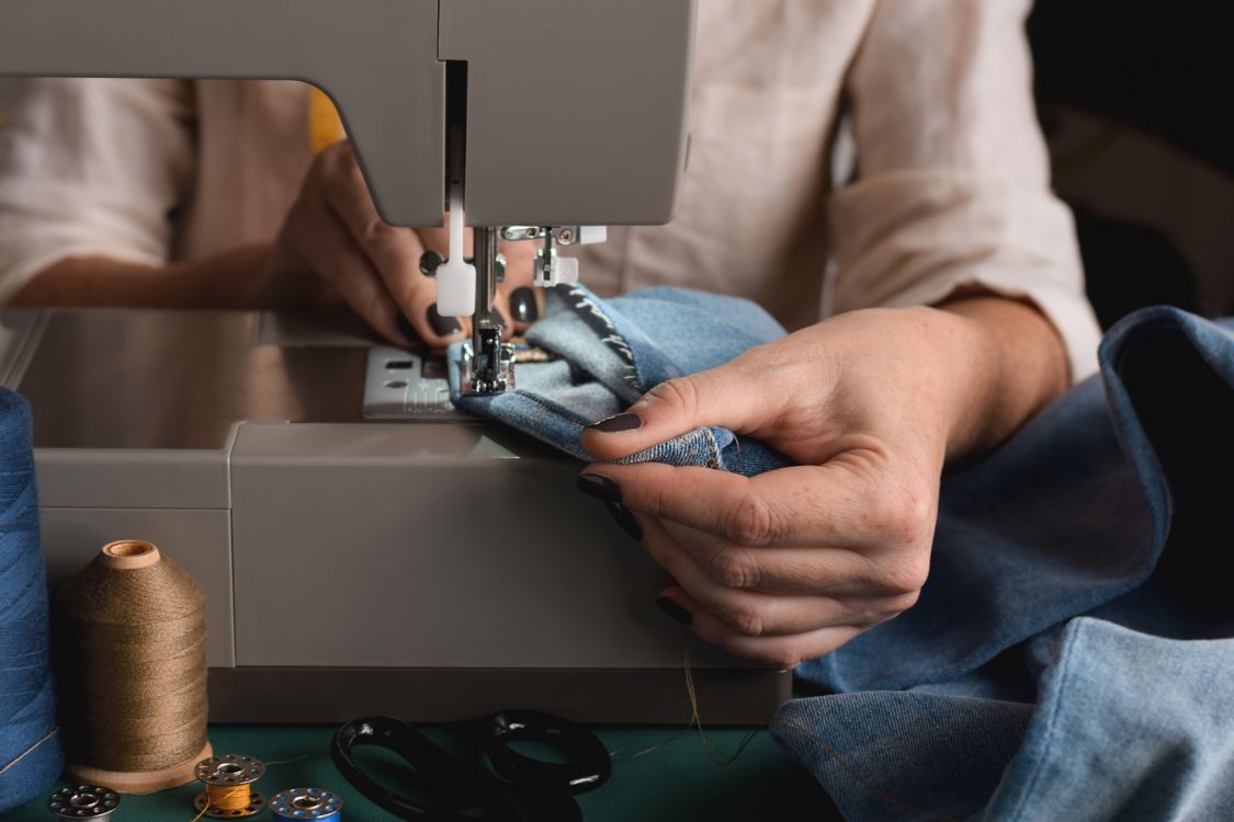 jean tailor hemming jeans with a sewing machine