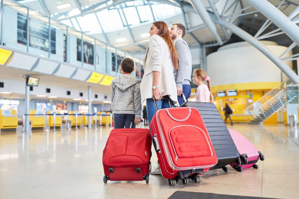 family walking through airport pulling suitcases