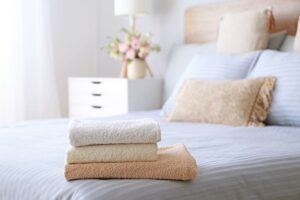 A clean guest bed with fresh folded bath towels on top, set up for holiday guests