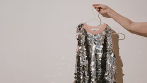 A silver sequined dress on a hanger with a do not dry clean label hidden on the inside
