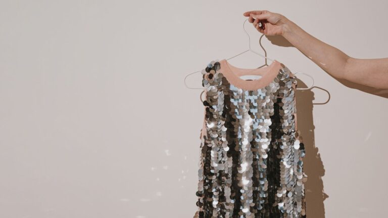 A silver sequined dress on a hanger with a do not dry clean label hidden on the inside